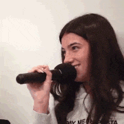 a woman is singing into a microphone while wearing a hoodie .