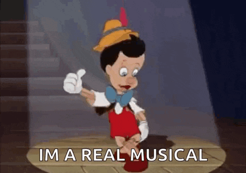 pinocchio is giving a thumbs up while standing on a stage .