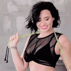 a woman in a black crop top is holding a jump rope around her neck .