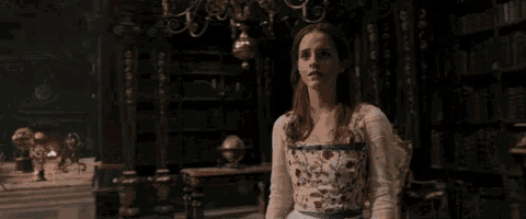 a woman in a white dress is standing in a room in a library .