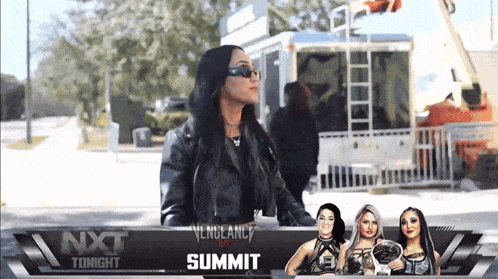 a woman stands in front of a sign that says nxt summit