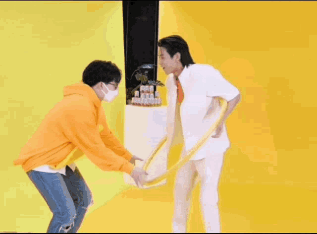a man in a white shirt and red tie is standing next to another man in an orange shirt .