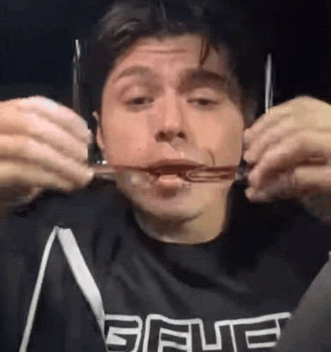a man wearing a blue shirt is eating a piece of food