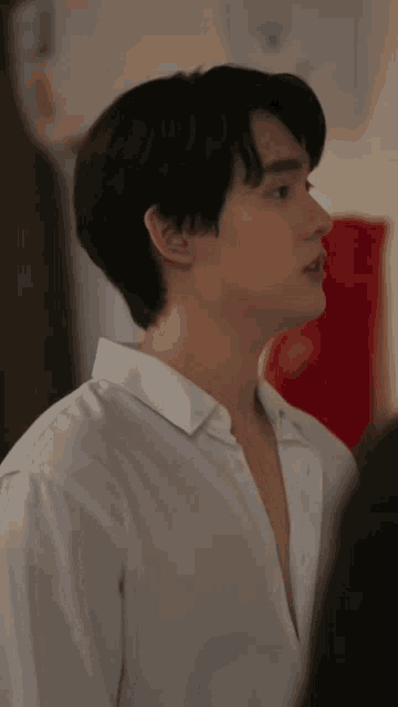 a man in a white shirt is standing in front of a red flag