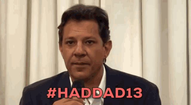 a man in a suit is talking into a microphone with the hashtag # haddad13 written in red