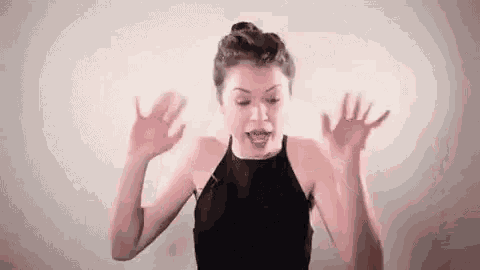 a woman in a black dress is making a funny face with her hands outstretched .