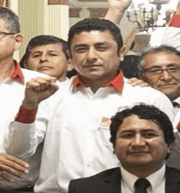 a man in a white shirt with a red collar is standing in a crowd of men