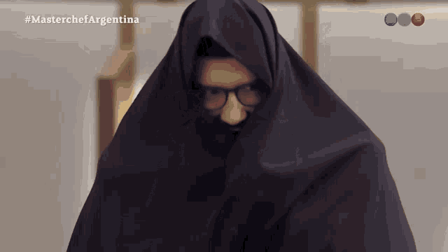 a man with glasses is covered in a black cloth with the hashtag #masterchefargentina on the bottom
