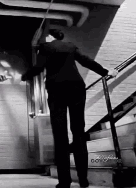 a man in a suit is walking up a set of stairs with the words the infamous governor on the bottom