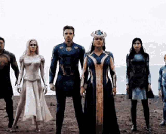 a group of people in superhero costumes are standing next to each other in a line .