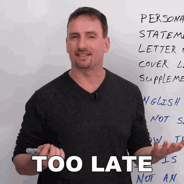 a man is standing in front of a white board with the words too late written on it