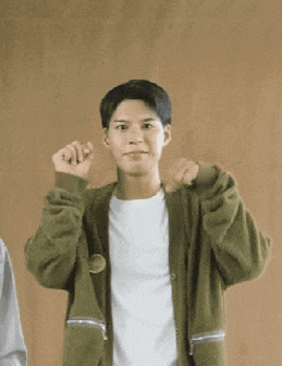 a young man wearing a green jacket and a white shirt