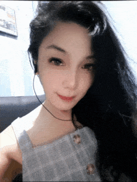 a woman wearing headphones and a plaid top is smiling