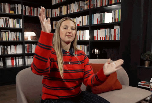 a woman in a red and black striped sweater sitting on a couch