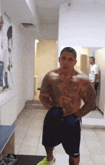 a shirtless man with a tattoo on his chest wearing adidas shorts