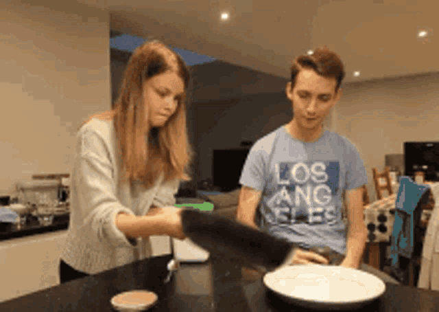 a boy wearing a los angeles t-shirt is standing next to a girl