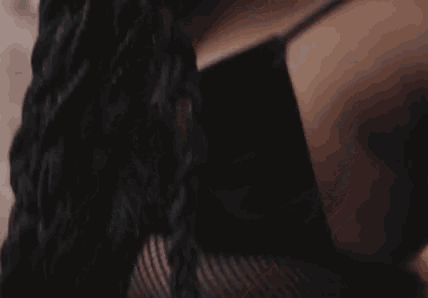 a woman with dreadlocks and hoop earrings is wearing a black top and earrings .