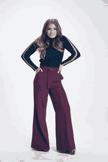 a woman wearing a black turtleneck and wide leg pants stands with her hands in her pockets