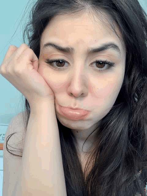 a woman making a sad face with her hand on her face