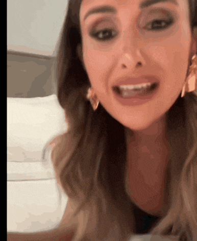 a woman wearing earrings is smiling and looking at the camera