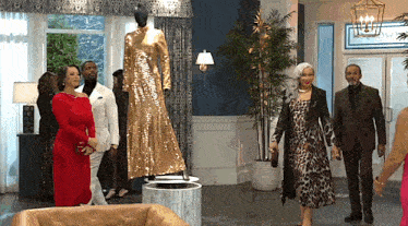 a group of people are standing around a mannequin wearing a gold dress .