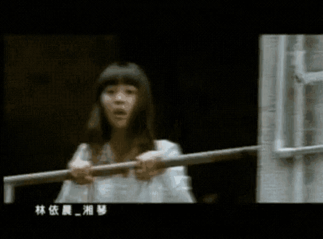 a girl is holding a railing with chinese writing on the bottom
