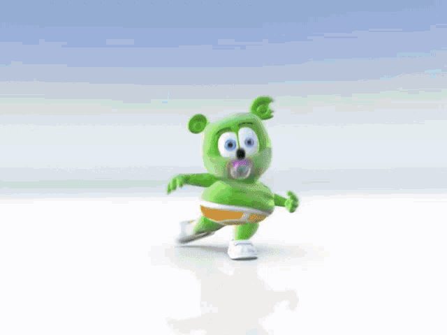a green gummy bear wearing white shoes is dancing on a white surface