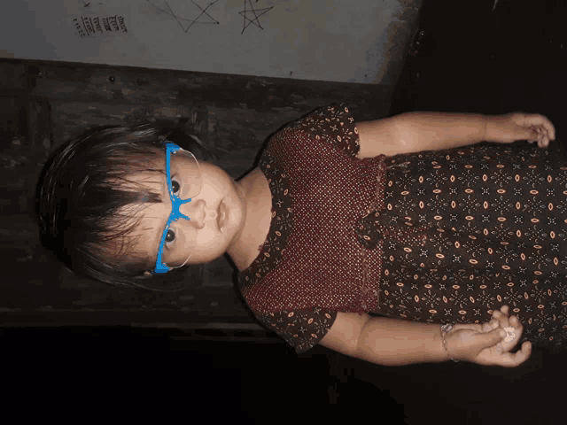a little girl wearing blue glasses and a dress