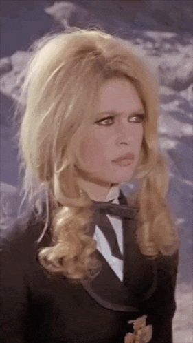 a woman with blonde hair is wearing a black jacket and tie
