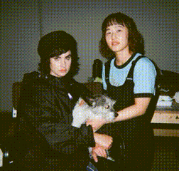 a woman is holding a small dog while another woman stands behind her