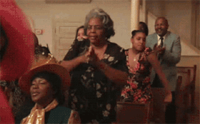 a group of people are clapping their hands in a room