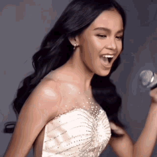 a woman singing into a microphone with her mouth wide open