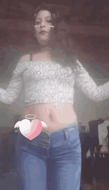 a woman wearing a crop top and jeans has a pink heart on her waist