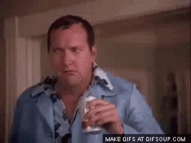 a man in a blue shirt is holding a glass and a can of soda .