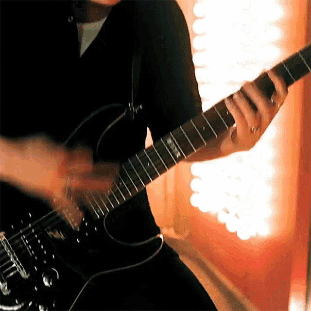 a man is playing an electric guitar in front of a wall of lights