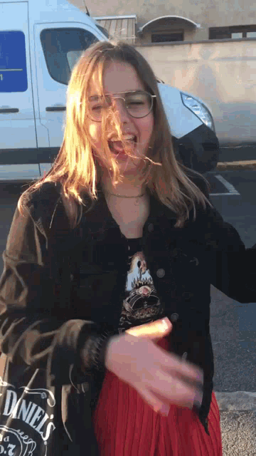 a woman wearing glasses and a daniel 's shirt laughs