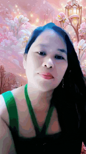 a woman in a green tank top stands in front of a pink background
