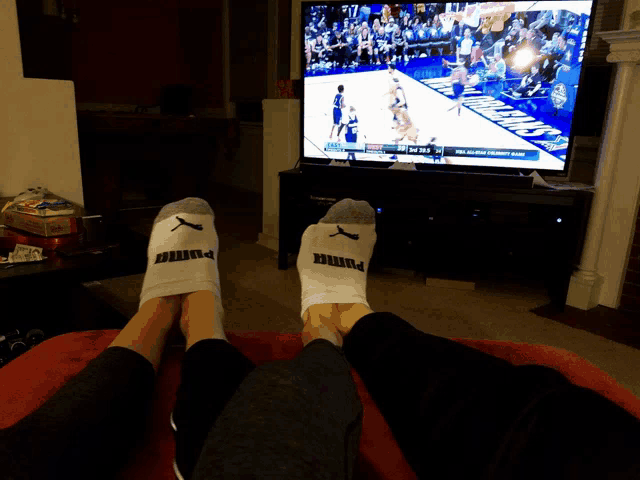 a person wearing a pair of puma socks watches a basketball game