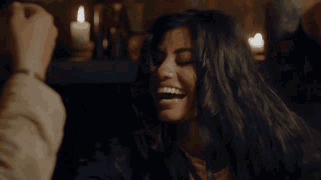 a woman is laughing while a man holds her hair
