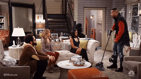 a group of people are sitting on a couch in a living room while a man is standing next to them .