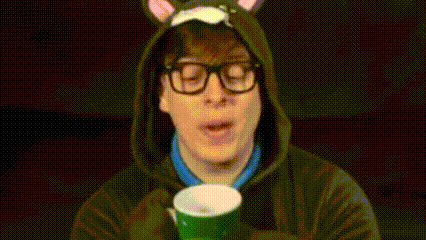 a man wearing a cat hoodie and glasses is holding a cup .