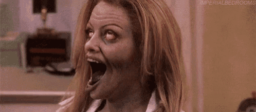 a woman is looking like a zombie with her mouth wide open and red eyes .