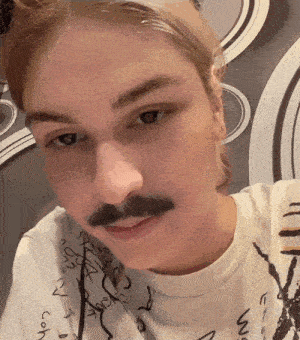 a close up of a person 's face with a mustache and a white shirt that says ' a '
