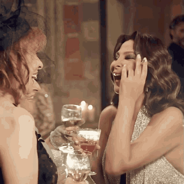 two women laughing while holding wine glasses