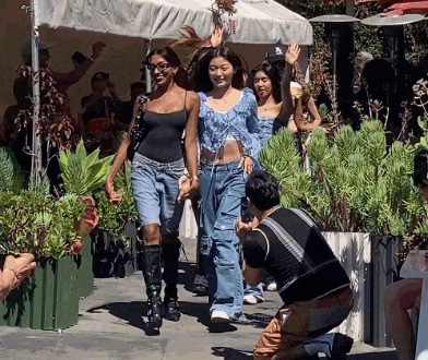 a man taking a picture of two women walking down a sidewalk