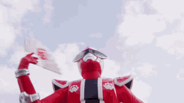a red superhero is holding a fan up in the air