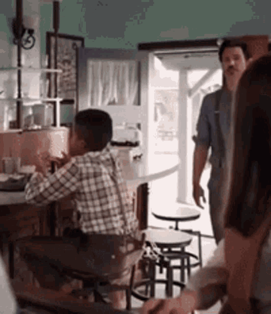 a man in a plaid shirt sits at a table in a restaurant