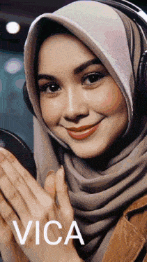 a woman wearing a hijab and headphones with the word vica on the bottom