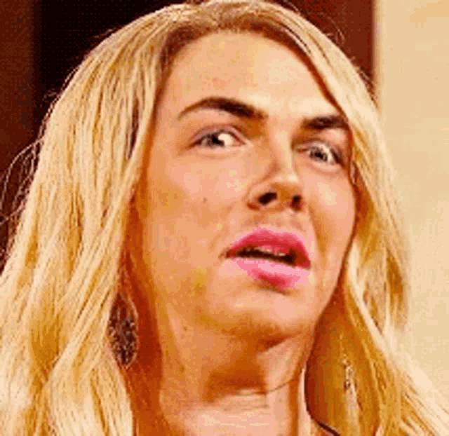 a close up of a woman 's face with blonde hair and pink lips making a funny face .