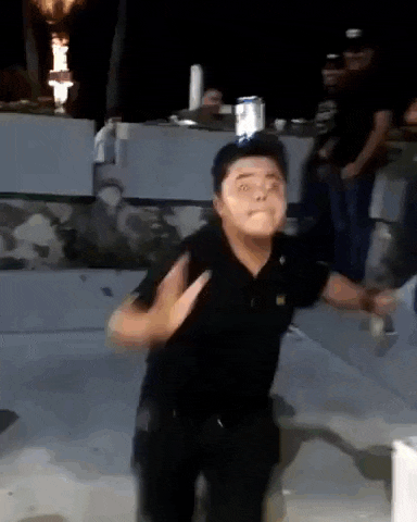 a man in a black shirt is making a funny face while dancing in front of a crowd .